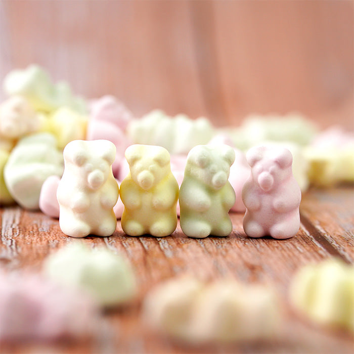 Oursons d'Alsace à la meringue : quatre oursons multicolores devant un tas d'oursons renversé sur table en bois