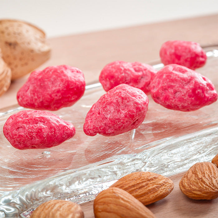 Pralines roses de Lyon aux amandes, confiserie artisanale lyonnaise, présentées sur fond bois et plaque de verre